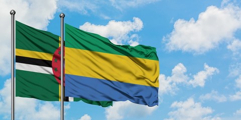 Dominica and Gabon flag waving in the wind against white cloudy blue sky together. Diplomacy concept, international relations.