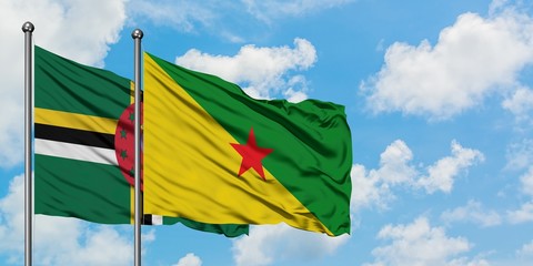 Dominica and French Guiana flag waving in the wind against white cloudy blue sky together. Diplomacy concept, international relations.