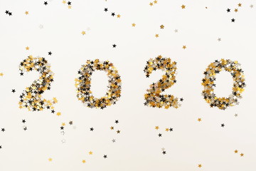 Christmas background. digits 2020 new year from gold black stars sparkles glitter on white background top view 