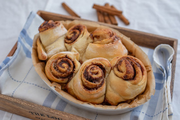 Cinnamon rolls with sugar frosting. With cinnamon sticks and spices, wooden background