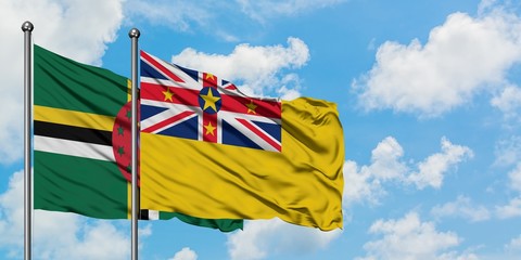 Dominica and Niue flag waving in the wind against white cloudy blue sky together. Diplomacy concept, international relations.