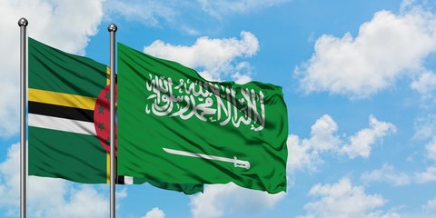 Dominica and Saudi Arabia flag waving in the wind against white cloudy blue sky together. Diplomacy concept, international relations.
