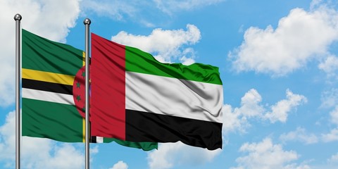 Dominica and United Arab Emirates flag waving in the wind against white cloudy blue sky together. Diplomacy concept, international relations.