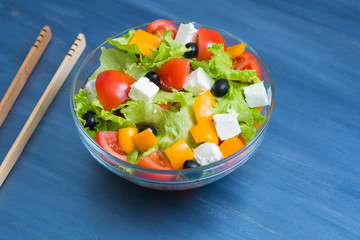 Greek salad in glass bowl on dark gray wooden or metal table