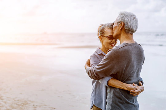 Asian Senior Couple Or Elderly People Walking And Siting At The Beach On Their Weekend Vacation Holiday. Retirement Vaction Concept.