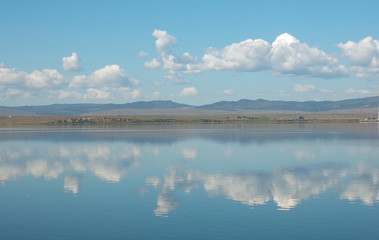 Lake in the mountains with forest. Wide-angle image of a lake with mountains in the background and reflections in the water. Beautiful scenery. Lake in Transbaikalia.