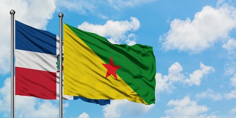Dominican Republic and French Guiana flag waving in the wind against white cloudy blue sky together. Diplomacy concept, international relations.