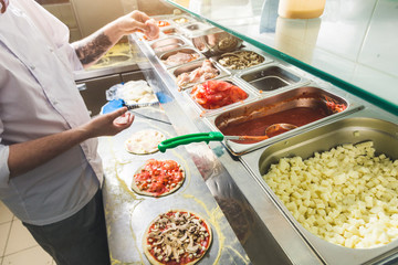 Professional chef cooking in the kitchen restaurant at the hotel, preparing dinner. A cook in an apron makes a salad of vegetables and pizza.