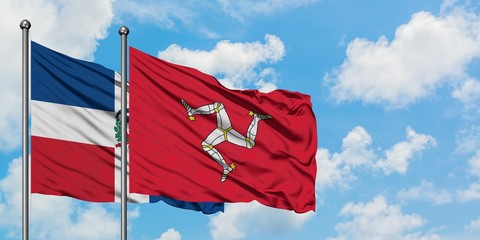 Dominican Republic and Isle Of Man flag waving in the wind against white cloudy blue sky together. Diplomacy concept, international relations.