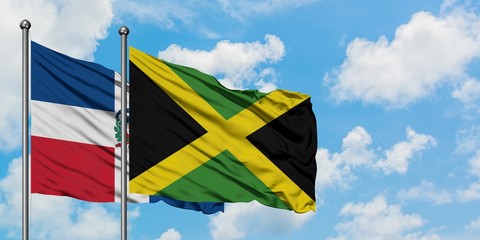 Dominican Republic and Jamaica flag waving in the wind against white cloudy blue sky together. Diplomacy concept, international relations.