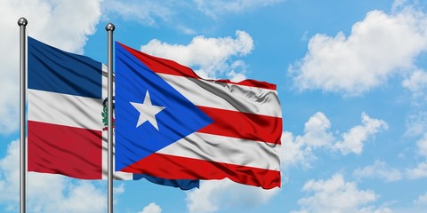 Dominican Republic and Puerto Rico flag waving in the wind against white cloudy blue sky together. Diplomacy concept, international relations.