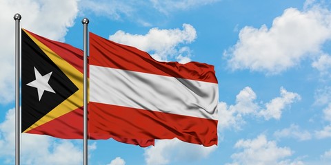 East Timor and Austria flag waving in the wind against white cloudy blue sky together. Diplomacy concept, international relations.