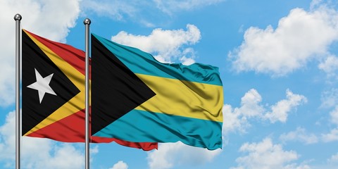 East Timor and Bahamas flag waving in the wind against white cloudy blue sky together. Diplomacy concept, international relations.