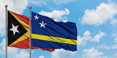 East Timor and Curacao flag waving in the wind against white cloudy blue sky together. Diplomacy concept, international relations.