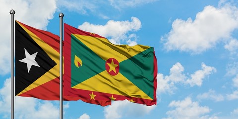 East Timor and Grenada flag waving in the wind against white cloudy blue sky together. Diplomacy concept, international relations.