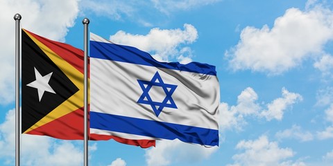 East Timor and Israel flag waving in the wind against white cloudy blue sky together. Diplomacy concept, international relations.