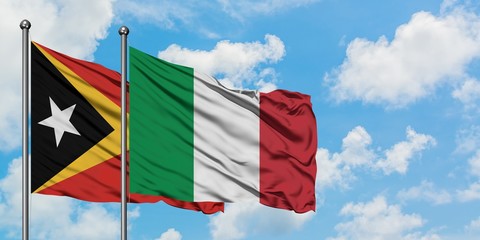 East Timor and Italy flag waving in the wind against white cloudy blue sky together. Diplomacy concept, international relations.