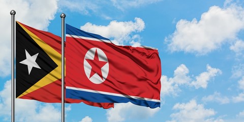 East Timor and North Korea flag waving in the wind against white cloudy blue sky together. Diplomacy concept, international relations.
