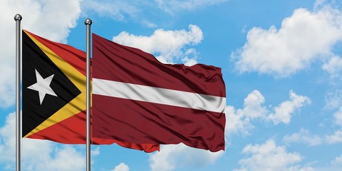 East Timor and Latvia flag waving in the wind against white cloudy blue sky together. Diplomacy concept, international relations.