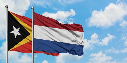 East Timor and Netherlands flag waving in the wind against white cloudy blue sky together. Diplomacy concept, international relations.