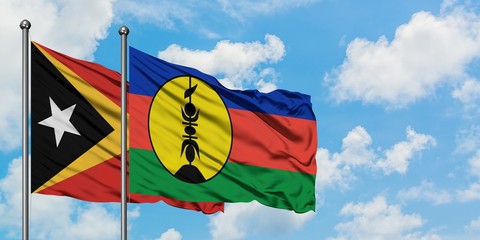 East Timor and New Caledonia flag waving in the wind against white cloudy blue sky together. Diplomacy concept, international relations.
