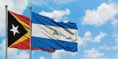East Timor and Nicaragua flag waving in the wind against white cloudy blue sky together. Diplomacy concept, international relations.