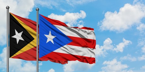 East Timor and Puerto Rico flag waving in the wind against white cloudy blue sky together. Diplomacy concept, international relations.