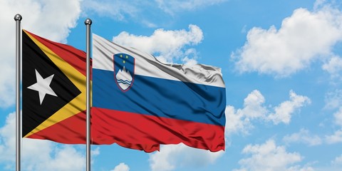 East Timor and Slovenia flag waving in the wind against white cloudy blue sky together. Diplomacy concept, international relations.