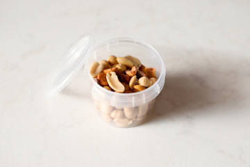 Salted peanuts in clear circle plastic container. Delicious and healthy snack for vegetarians, good with beer.