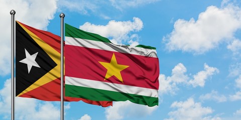 East Timor and Suriname flag waving in the wind against white cloudy blue sky together. Diplomacy concept, international relations.