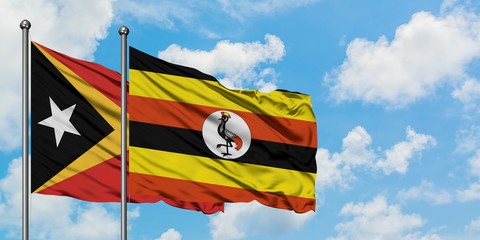 East Timor and Uganda flag waving in the wind against white cloudy blue sky together. Diplomacy concept, international relations.