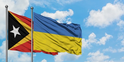 East Timor and Ukraine flag waving in the wind against white cloudy blue sky together. Diplomacy concept, international relations.