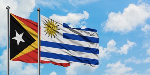 East Timor and Uruguay flag waving in the wind against white cloudy blue sky together. Diplomacy concept, international relations.