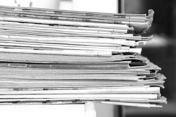 Pile of fresh morning newspapers on the table at office. Latest financial and business news in daily paper. Pages with information (headlines, articles, photos, text). Folded and stacked journals    