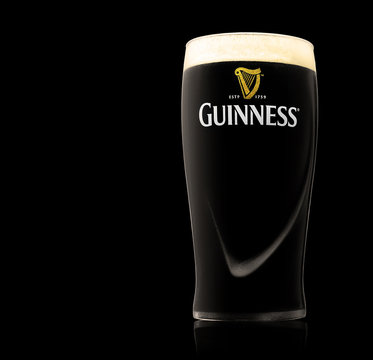 POLTAVA, UKRAINE - OCTOBER 4, 2017:Glass of Guinness original beer on black background. Guinness beer has been produced since 1759 in Dublin, Ireland.