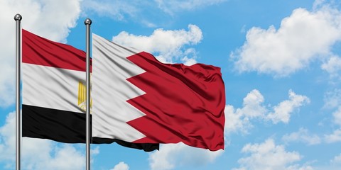 Egypt and Bahrain flag waving in the wind against white cloudy blue sky together. Diplomacy concept, international relations.