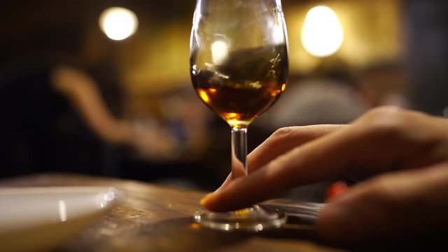 This close up video shows an anonymous hand swirling vermouth sherry in glass at an elegant traditional restaurant in Spain.