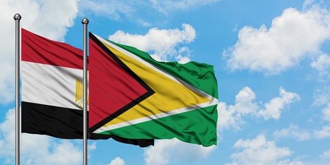 Egypt and Guyana flag waving in the wind against white cloudy blue sky together. Diplomacy concept, international relations.