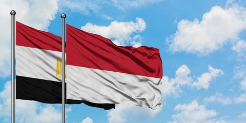 Egypt and Monaco flag waving in the wind against white cloudy blue sky together. Diplomacy concept, international relations.