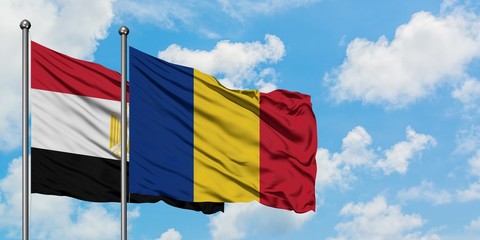 Egypt and Romania flag waving in the wind against white cloudy blue sky together. Diplomacy...