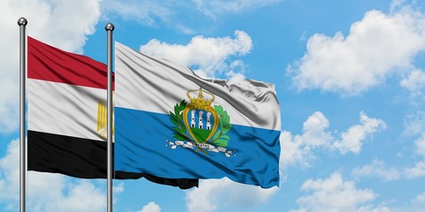 Egypt and San Marino flag waving in the wind against white cloudy blue sky together. Diplomacy...