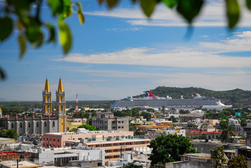 High vantage point of downtown Mazatlan with a large cruise ship docked at the harbor and an old church in the middle - 300826591