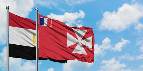 Egypt and Wallis And Futuna flag waving in the wind against white cloudy blue sky together. Diplomacy concept, international relations.
