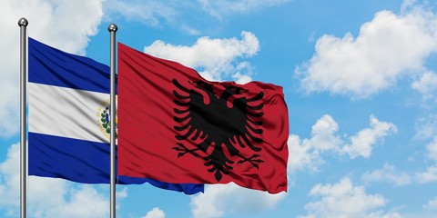 El Salvador and Albania flag waving in the wind against white cloudy blue sky together. Diplomacy concept, international relations.