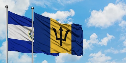 El Salvador and Barbados flag waving in the wind against white cloudy blue sky together. Diplomacy concept, international relations.