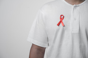 closeup of a young man with a red awareness ribbon for the fight against AIDS in his hand