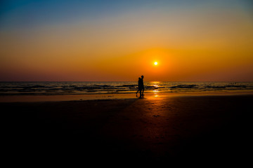 Siluate lovers and beach before sunset