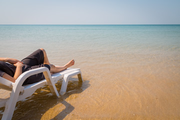 Vacation on tropical beach Woman's legs on the beach bed with clear ocean water