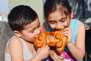 Latin kids eating tantawawa - typical sweet bread for All Saints Day.