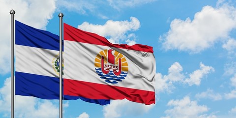 El Salvador and French Polynesia flag waving in the wind against white cloudy blue sky together. Diplomacy concept, international relations.